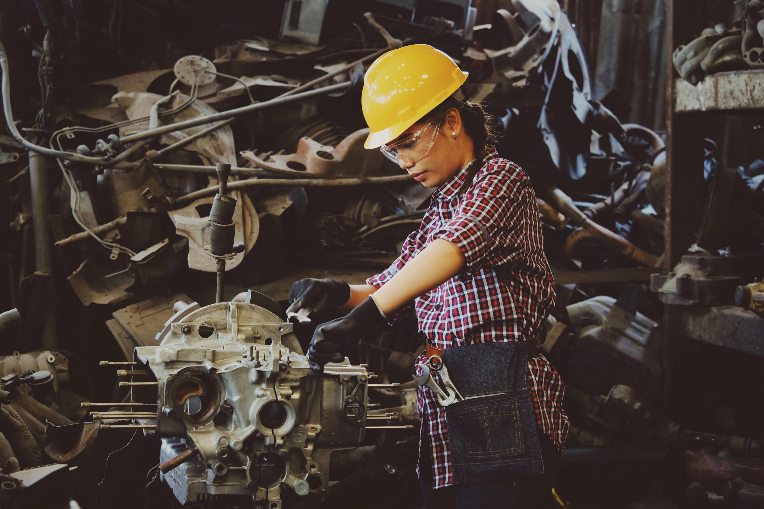Woman wearing safety gear, working on metal recycling.